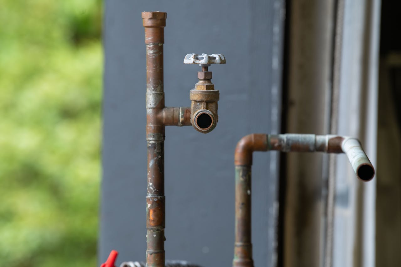Mastering the First Impression: Your intriguing post title goes here Detailed view of an old, rusty industrial water pipe with valve, conveying vintage industrial aesthetics.